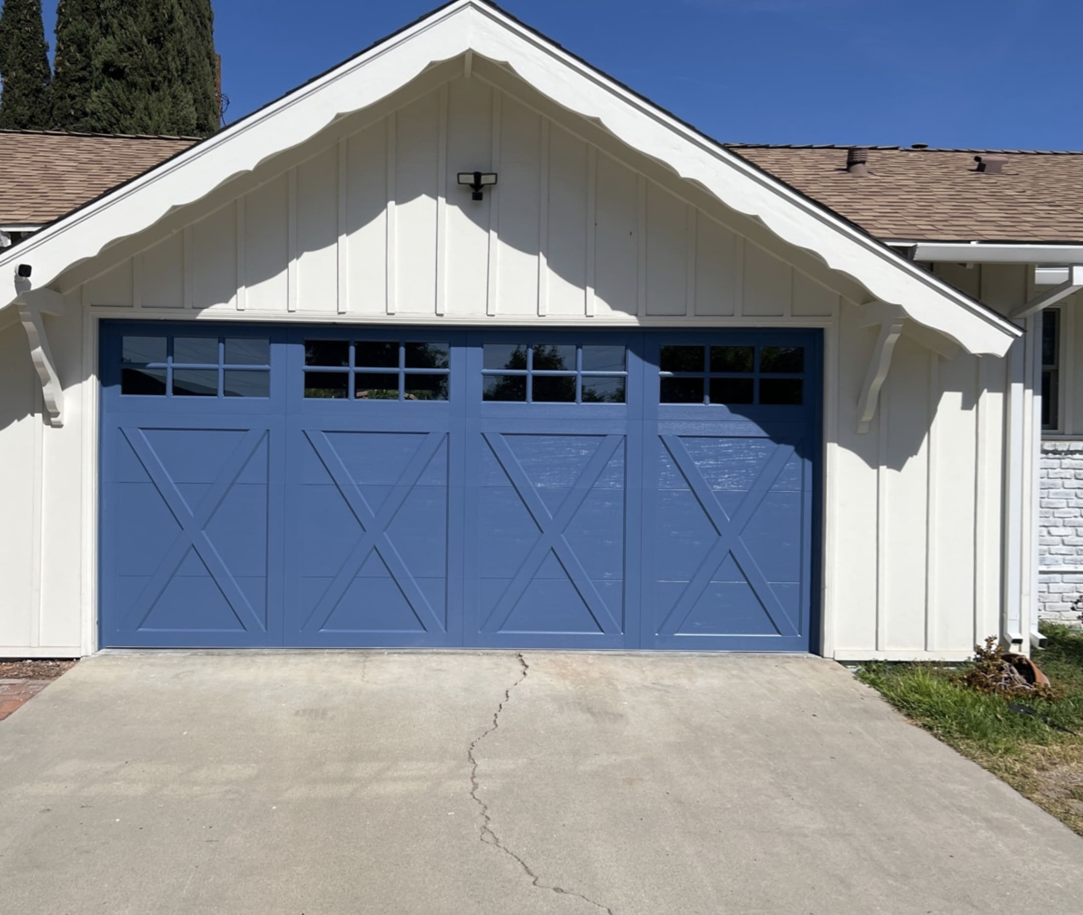 Screenshot Blue carriage-style garage door on a white home, showcasing a clean and well-maintained exterior.